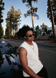 Issac Ryan Brown standing outside house in blue outfit pop R&B singer portrait