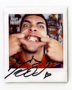 Milo J close-up portrait showing gold grills smiling during NPR Tiny Desk performance