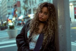 Bella Kay leaning against pole in city street during Promise single era photoshoot