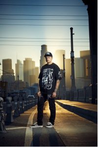 Ryan Oakes standing on bridge with Los Angeles skyline at sunset