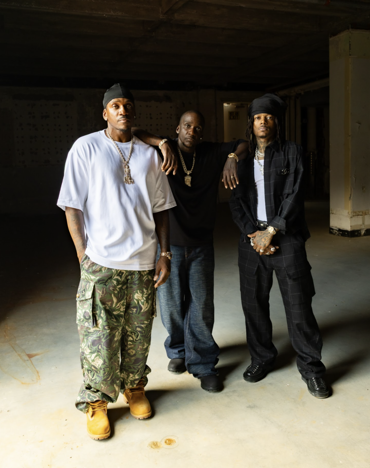 Clipse members Pusha T and Malice pose with rapper J.I.D in an industrial warehouse setting ahead of their 2026 Red Rocks Amphitheatre concert announcement.