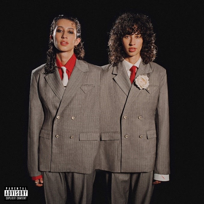 Towa Bird appears in mirrored tailoring on the cover of her 2026 album Gentleman, standing beside a duplicate version of herself in matching gray suits and red ties.