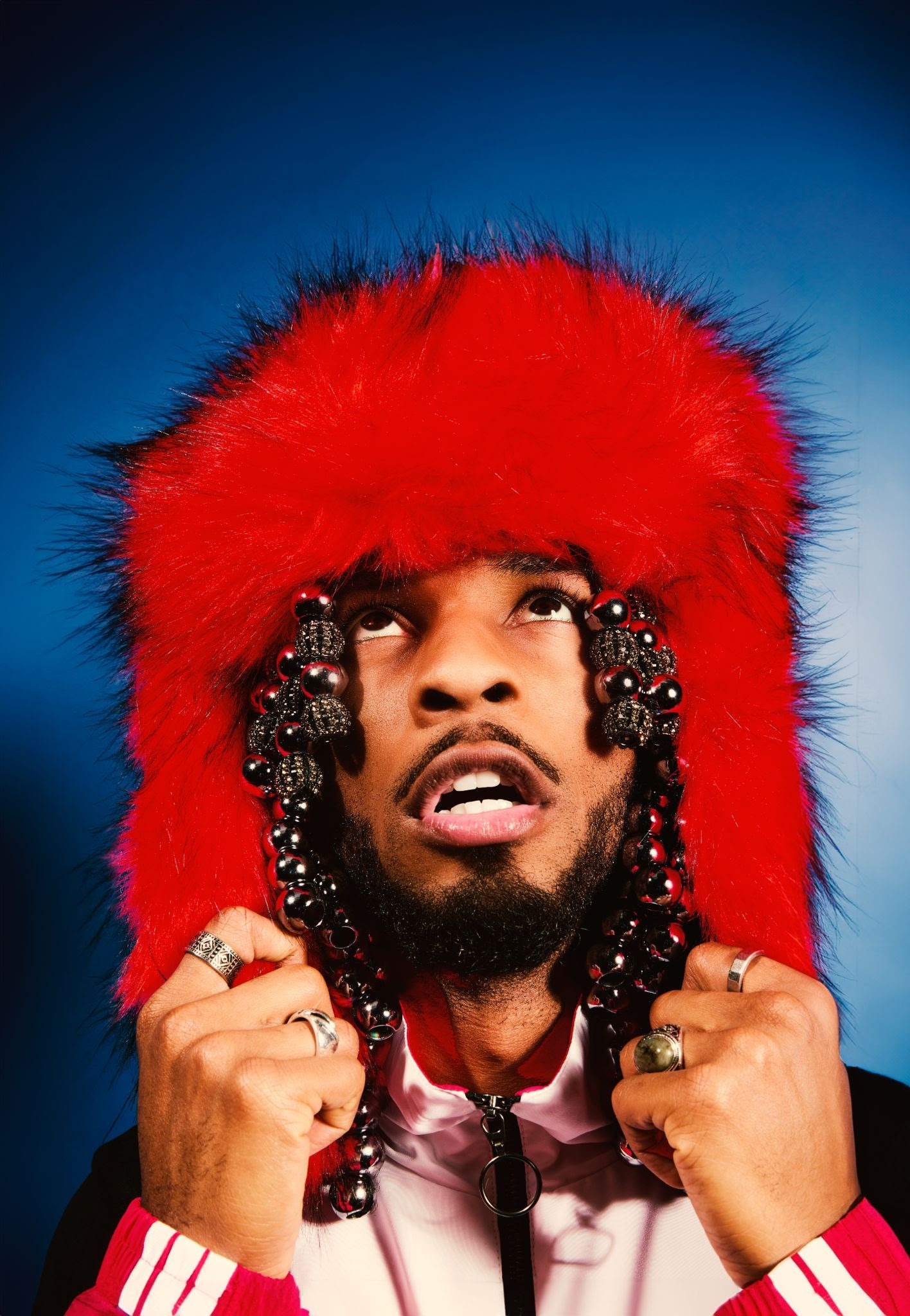 Armani White wearing a bright red fur hat with beaded details during a stylized portrait shoot for “[PRESS]”