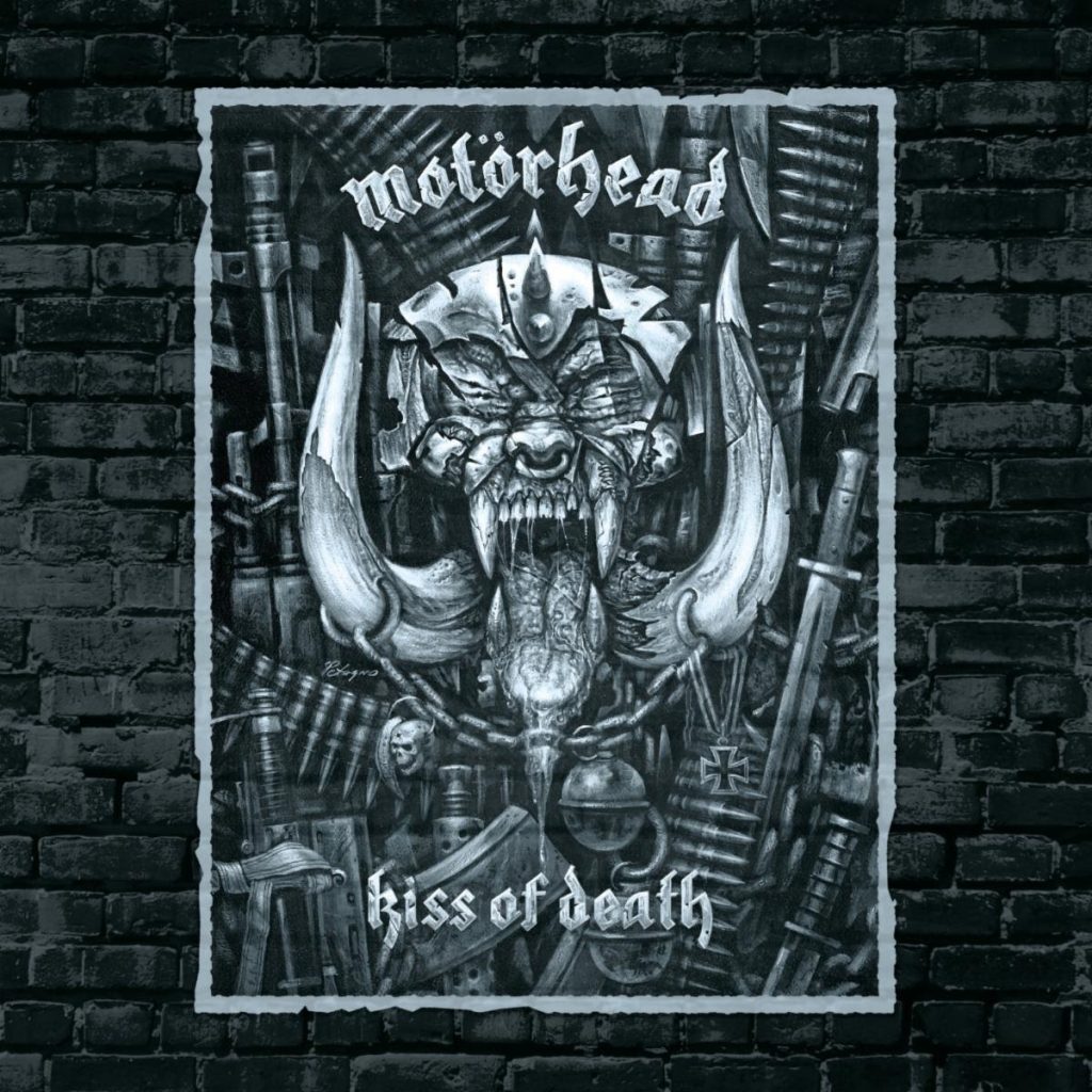 Motörhead Kiss of Death 20th Anniversary Edition artwork featuring the band's iconic Snaggletooth mascot surrounded by weapons, chains, bullets, and heavy metal imagery.