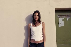 Charlotte Cardin stands against a sunlit wall during the promotional campaign for her single "Take Me Back"