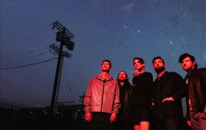 Beartooth band members pose outdoors at dusk ahead of the release of their 2026 album Pure Ecstasy