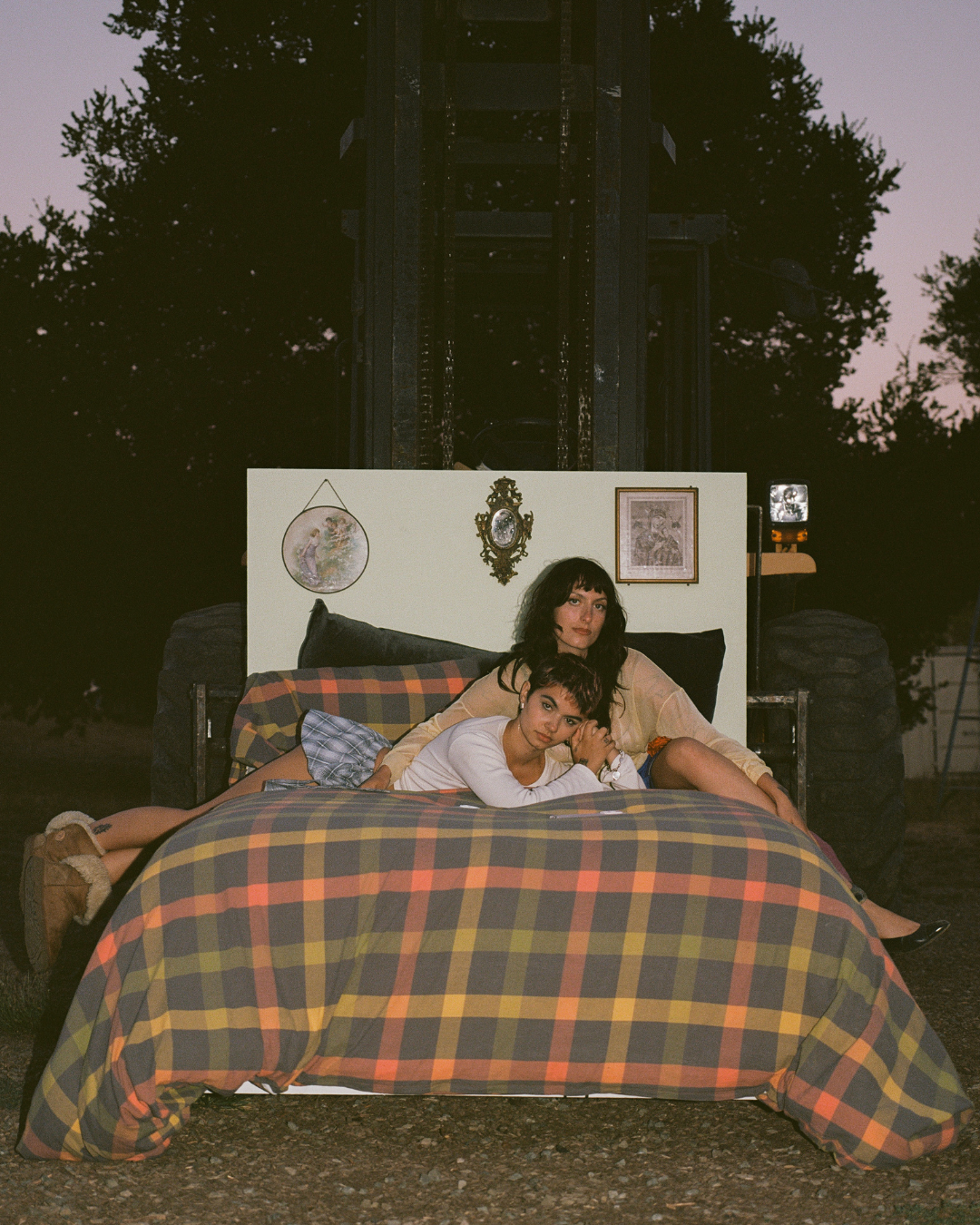 The Army The Navy members Maia Ciambriello and Sasha Goldberg posed on a bed outdoors during the Fake Brave Life album campaign