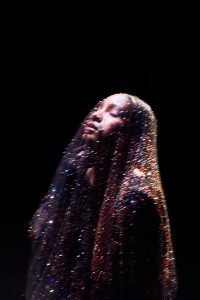 WILLOW poses beneath a shimmering veil in a promotional portrait by Sarah Binder ahead of her 2026 album The Thread.