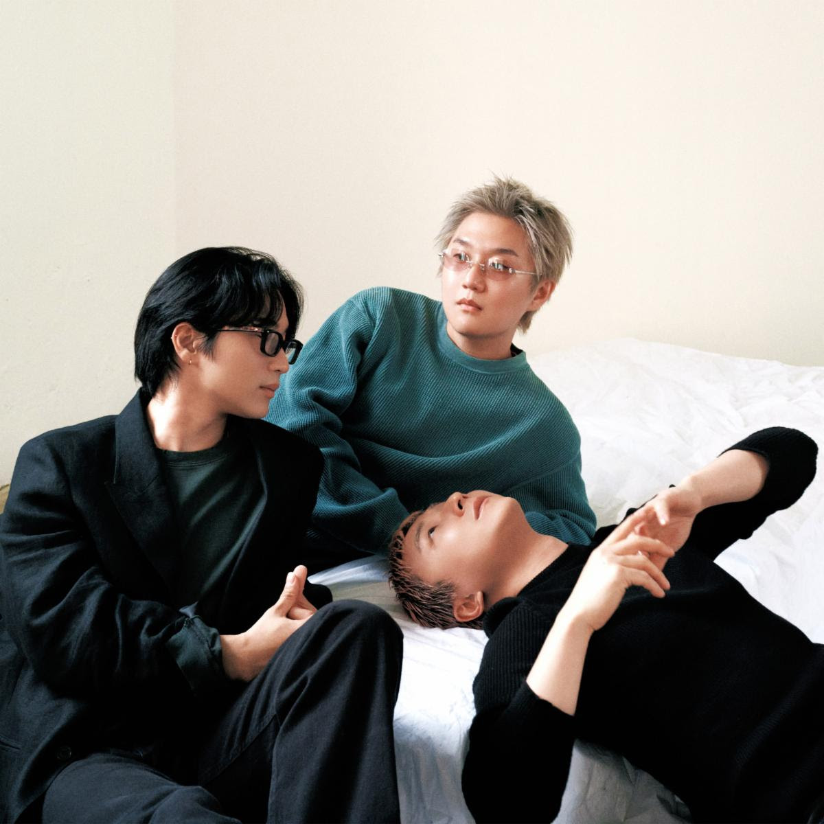 Members of Wave to Earth relax together on a bed in a minimalist room, photographed ahead of the release of their single "heaven and hell."