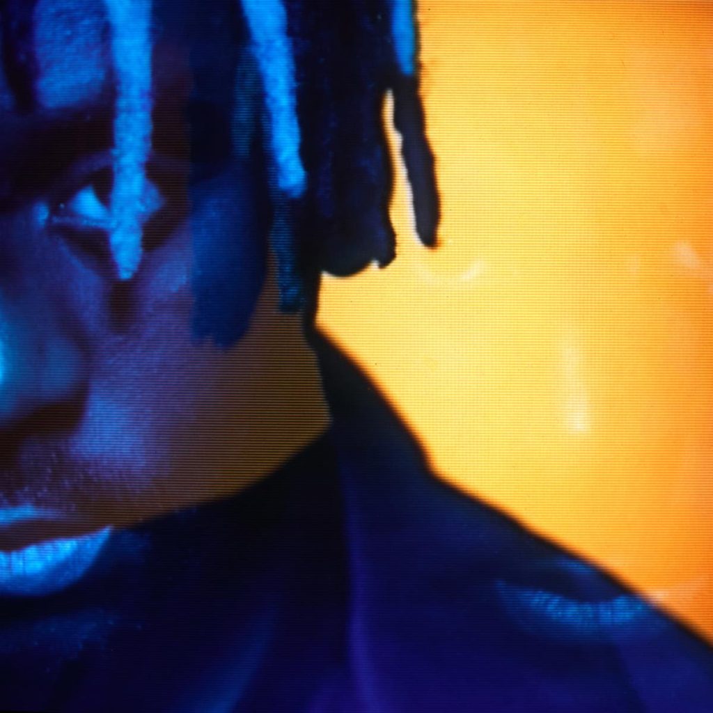 Close-up artistic portrait of Myles Smith illuminated by blue and orange lighting for his debut album campaign