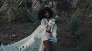 flowerovlove wears a flowing white veil while holding a lamb in a scene from the "American Wedding" music video