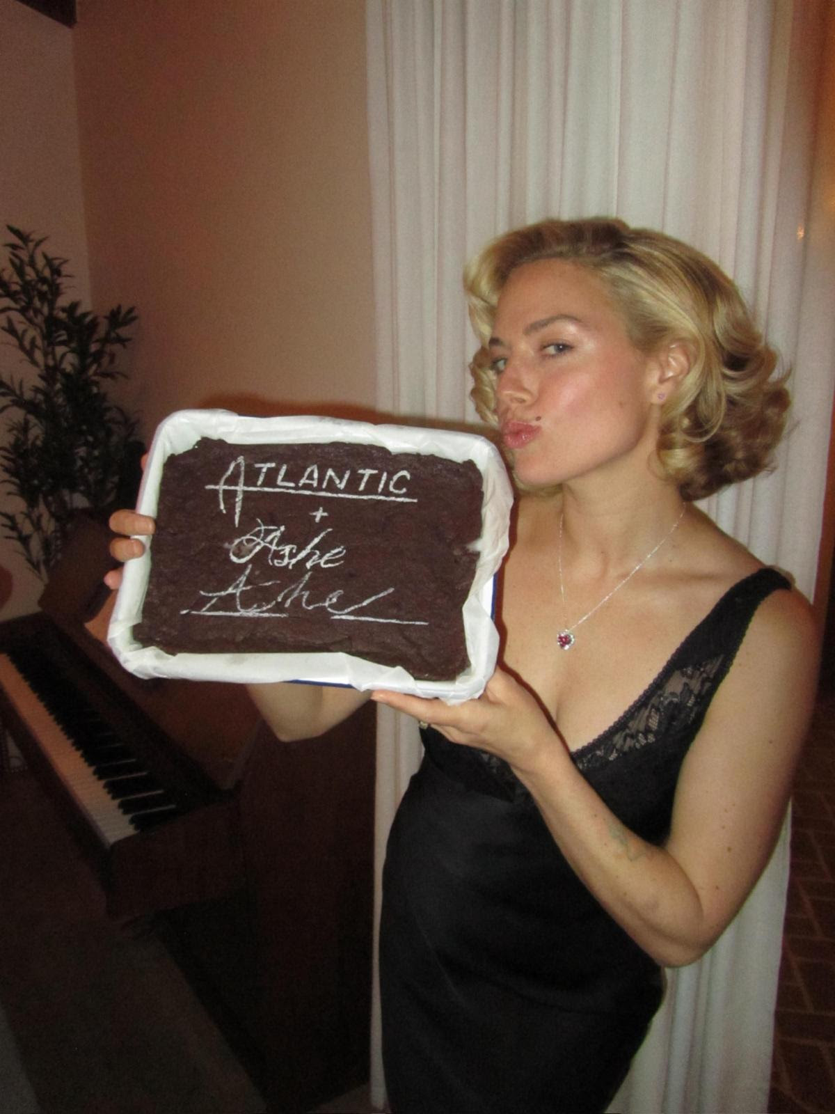 Ashe celebrates signing with Atlantic Records while holding a custom cake featuring the label's logo