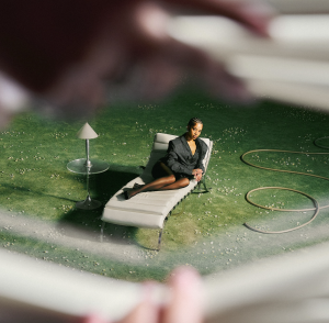 Ella Mai lounges on a chair in a garden setting in promotional artwork for her "Might Just" music video.