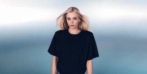Becky Hill poses in a black outfit in a promotional portrait for her upcoming album REBECCA.