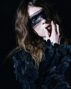 2hollis wears a black feathered outfit and lace eye mask in a dramatic promotional portrait for his 2026 single "Hurt."