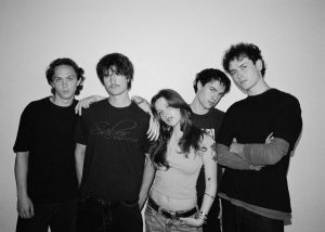 Porch Light band press photo 2026 featuring Jackie Uhas with Zac Fogarty, Henry Hughes, Kyle Siemon, and Tony O'Keefe ahead of the release of the single "Arctic."
