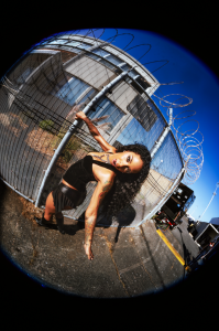 Rico Nasty poses beside a chain-link fence in a promotional photo for her 2026 album RX