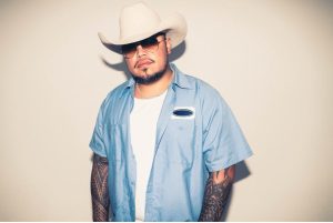 Hawaiian country reggae artist Maoli wearing a white cowboy hat and blue button-up shirt in a 2026 promotional portrait