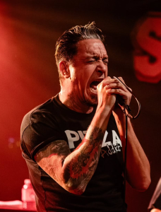 Lou Koller of Sick of It All passionately performs live on stage during a hardcore concert, singing into a microphone.