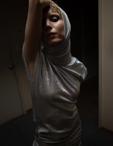 Lykke Li wearing a metallic silver hooded outfit in a 2026 promotional portrait for The Afterparty remix series.