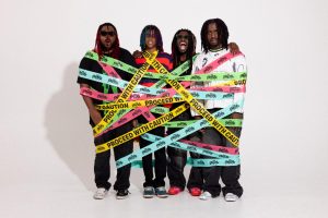 Atlanta rock band The Paradox pose wrapped in colorful Proceed With Caution tape to promote their 2026 EP.