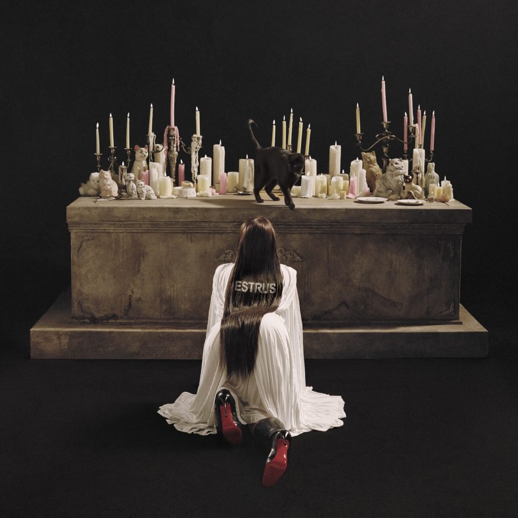 Tove Lo ESTRUS album cover featuring a candlelit altar, black cat, and the artist kneeling in a flowing white dress