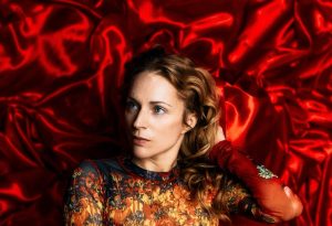 Agnes Obel photographed against red fabric for her 2026 album The Meaning of Flowers