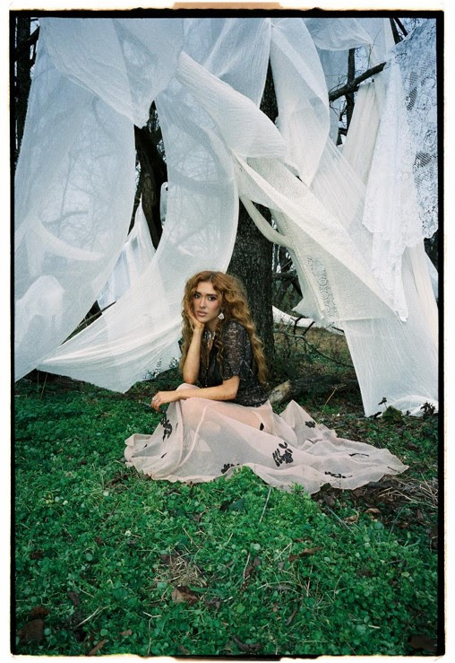 Laci Kaye Booth poses outdoors beneath flowing white fabric ahead of her album Love Ain’t For The Faint Of Heart.