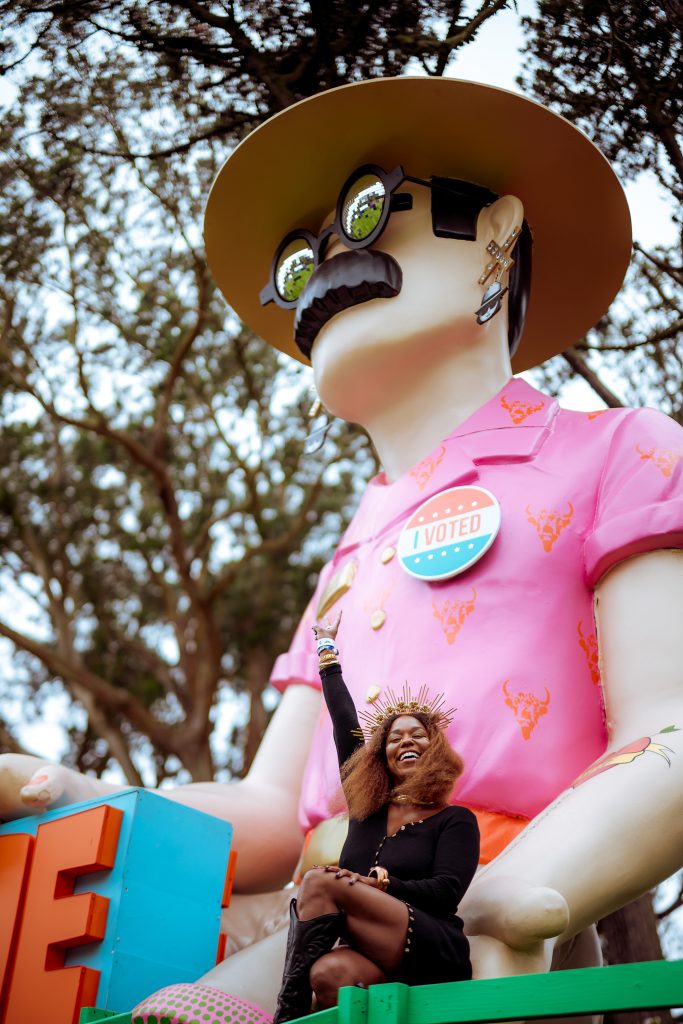 A festivalgoer poses beside a colorful oversized art installation at Outside Lands 2026.
