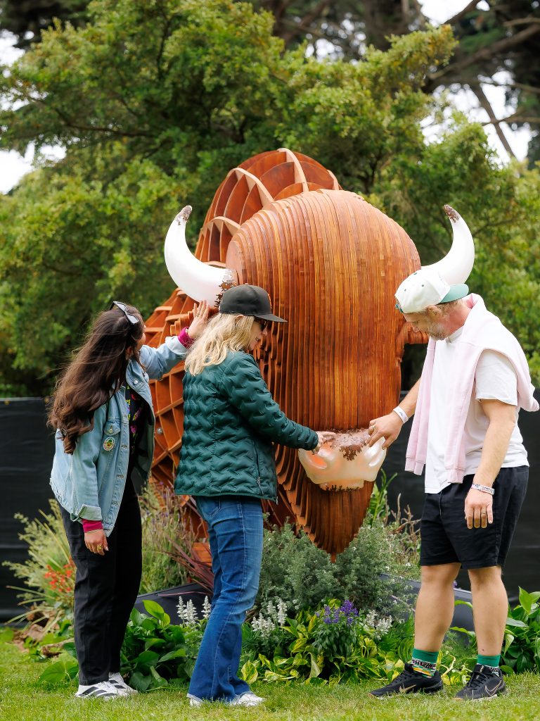 Festivalgoers interact with a large wooden bison art installation at Outside Lands 2026.