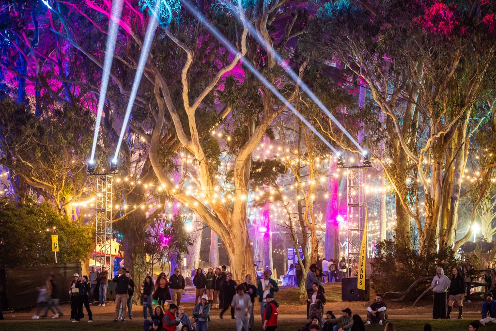 Colorful lights and spotlights illuminate the trees and festival grounds at Outside Lands 2026 in Golden Gate Park.