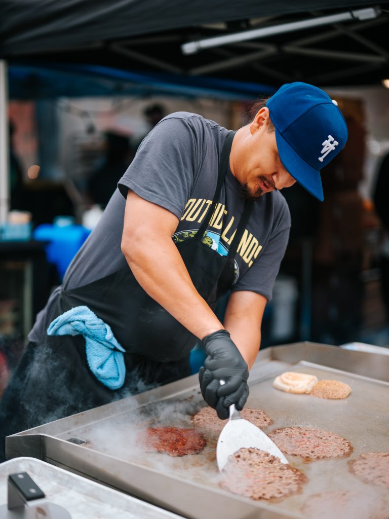 Chef cooks burgers on a flat-top grill at Outside Lands 2026 in San Francisco.