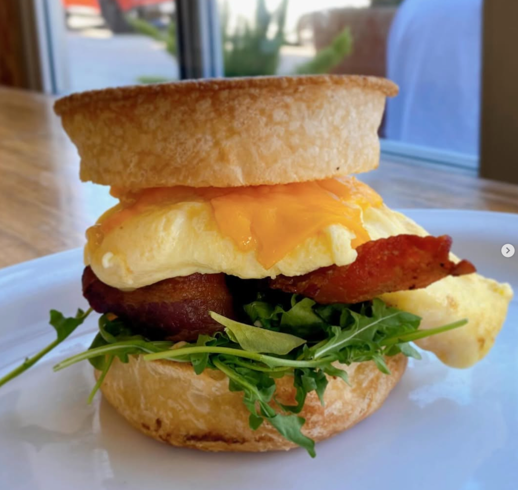 Breakfast sandwich with fluffy eggs, cheddar cheese, bacon and arugula on toasted bread from Park Cafe Group.