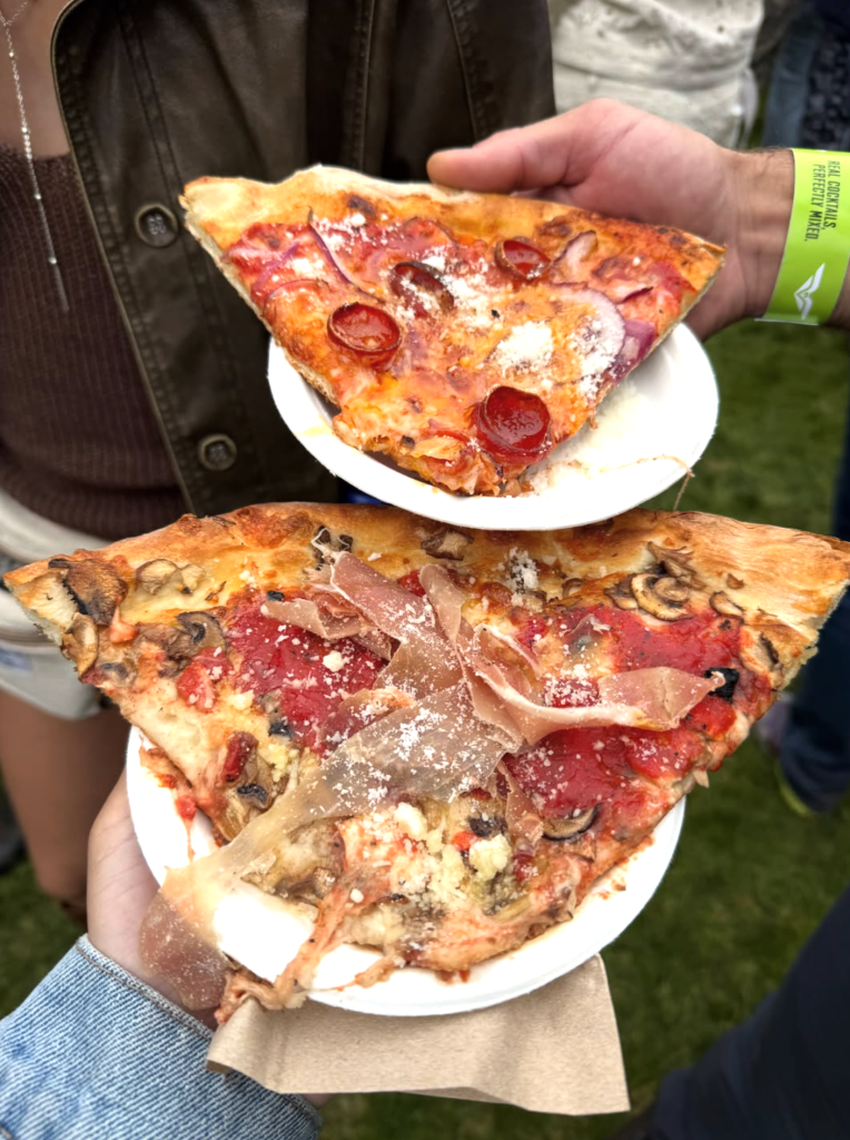 Two oversized slices of Pink Onion pizza topped with pepperoni, mushrooms and cured meats at Outside Lands 2026.