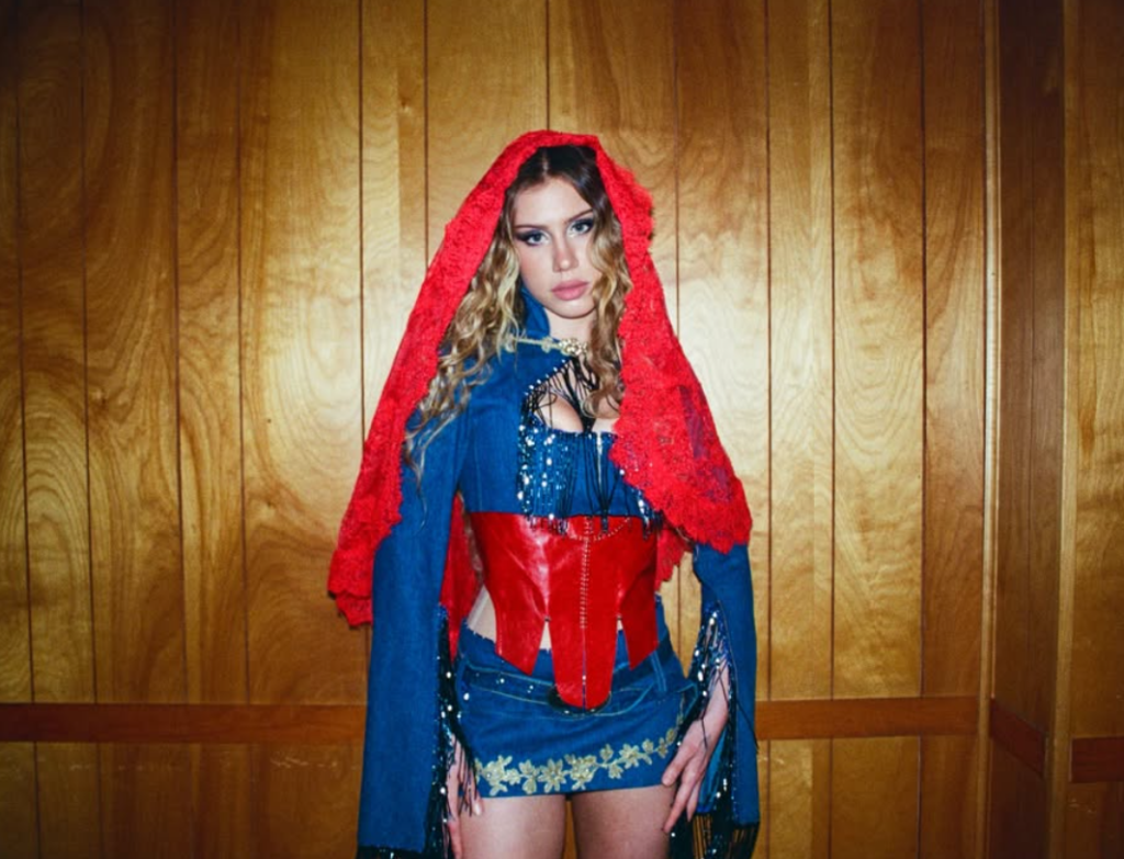 Slayyyter poses in a red, blue and denim outfit ahead of her September 2026 Oakland concert.
