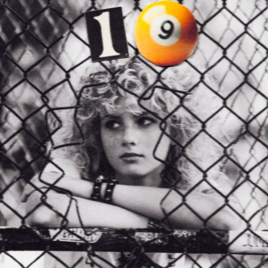 Guitarist and singer Grace Bowers with voluminous curly blonde hair, wearing a white D.A.R.E. T-shirt and silver chain necklaces against a dark background.